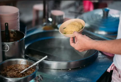 Street vendor preparing noodles at a Bangkok food stall