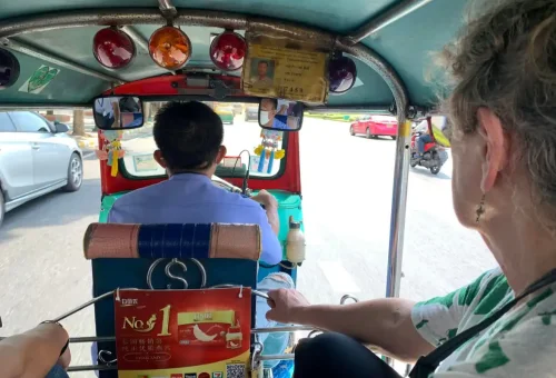 Tourist riding in a tuk-tuk through Chinatown streets