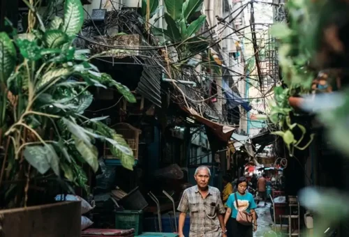 Narrow alley in Bangkok Chinatown with locals and plants