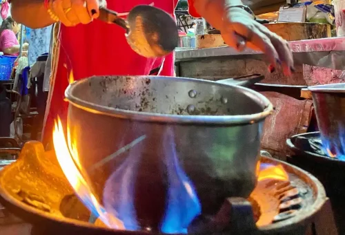 Close-up of street vendor cooking with open flame at night market