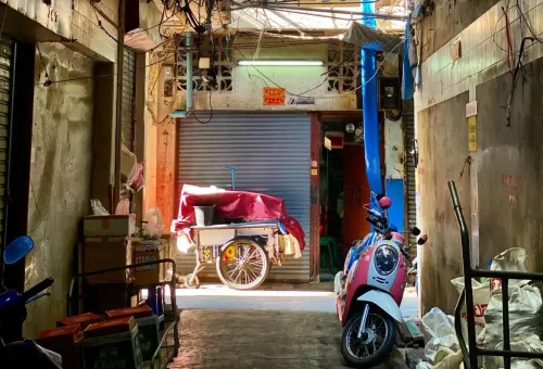 Alley in Chinatown Bangkok with parked scooter and food cart