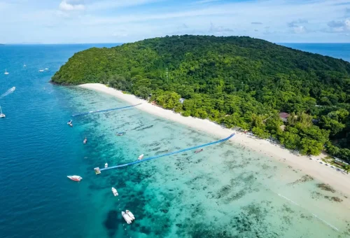 Aerial view of Coral Island beach with turquoise water, boats, and lush greenery near Phuket – Phuket Travel Store
