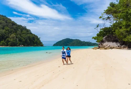 Couple walking on a quiet white sand beach at Surin Islands