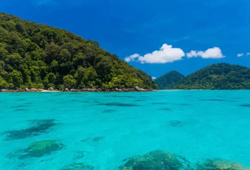 Crystal-clear turquoise sea and green island hills at Surin Islands