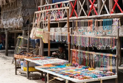Colorful handmade jewelry and woven bags at a traditional Moken village market stall