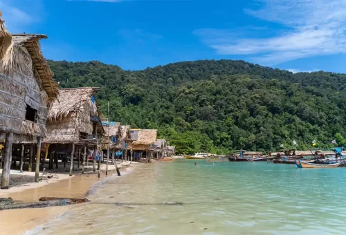 Seaside Moken village with traditional huts on stilts and longtail boats at Surin Islands, Thailand.