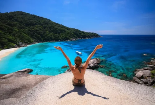 Woman with arms raised enjoying the panoramic ocean view at Similan Islands.