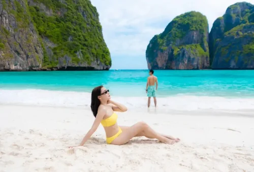 Woman sunbathing and man admiring the sea at Maya Bay, Thailand