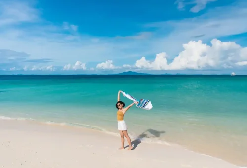 Woman enjoying the white sandy beach and turquoise sea at Bamboo Island.