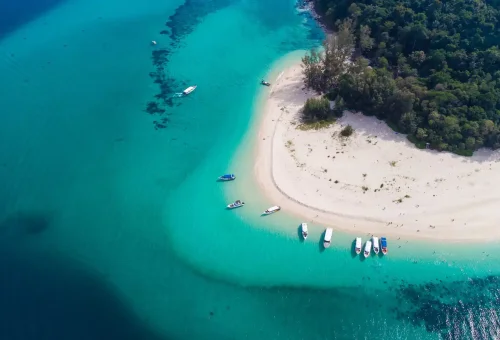 Turquoise shallows surrounding Bamboo Island with speedboats docked.
