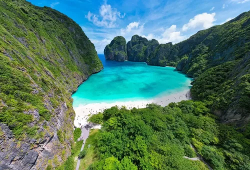 Aerial shot of Maya Bay with emerald water and lush cliffs.