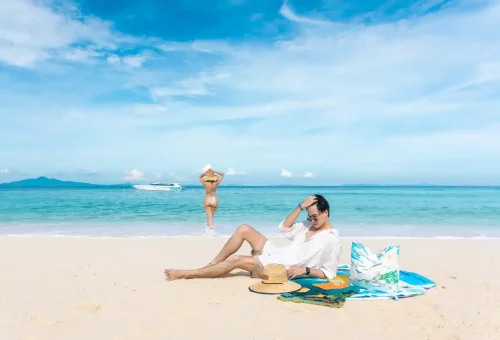 Couple enjoying a relaxing moment on the beach with speedboat nearby.
