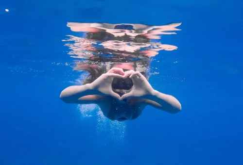 Underwater shot of a woman making a heart sign while snorkeling.