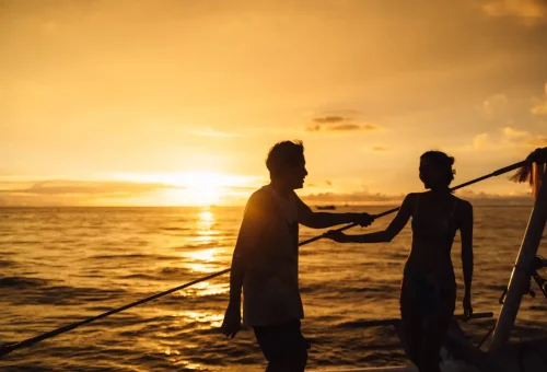 Couple enjoying a romantic sunset on the deck of a catamaran near Coral Island.