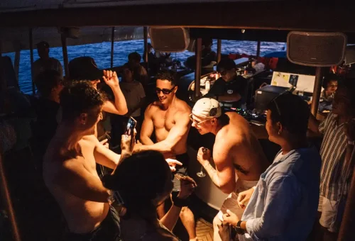 Guests enjoying a lively party with music and drinks onboard the sunset yacht cruise.