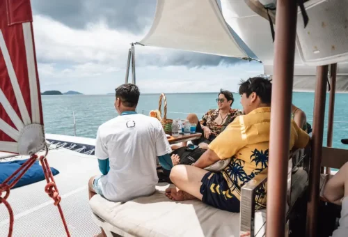 Friends relaxing in shaded seating on Ombre Yacht during scenic sailing tour.