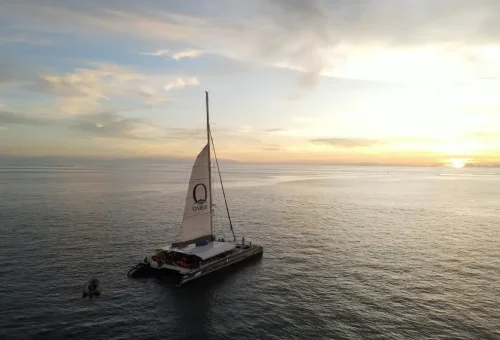 Ombre luxury catamaran sailing at sunset with glowing sky over Andaman waters.
