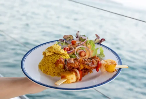 Gourmet meal of yellow rice, grilled skewers, and salad on boat