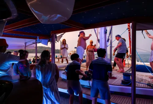 Guests dancing under vibrant lights on Ombre yacht during sunset party