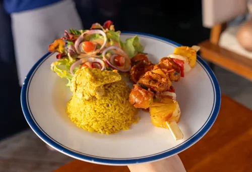 Chicken skewers with yellow rice and garden salad on white plate
