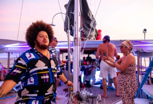 Guests dancing and enjoying a vibrant sunset party on the catamaran deck