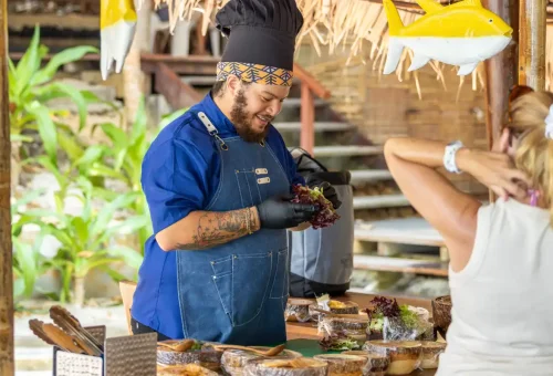Smiling chef preparing fresh salads at beachfront food station