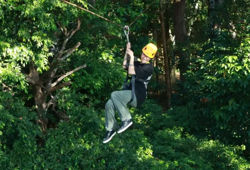 A woman riding solo on a zipline through green jungle at Flying Hanuman, Phuket.
