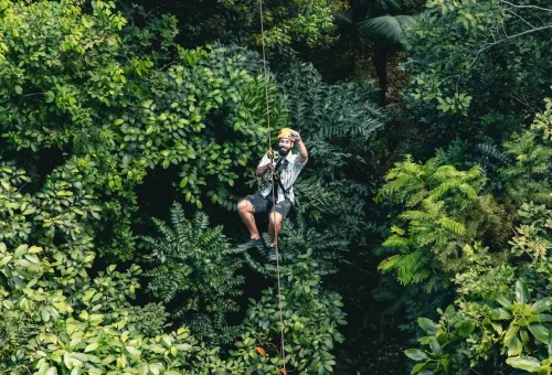 Solo zipliner gliding above lush green jungle foliage in Phuket.