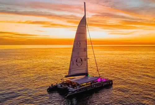 Luxury catamaran sailing at sunset with glowing sky over Andaman waters.