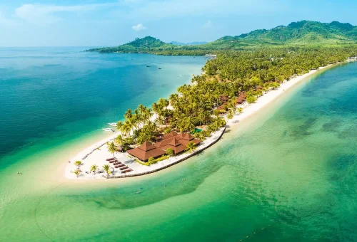 Aerial view of Koh Mook island with tropical beach, palm trees, and emerald green water in Thailand