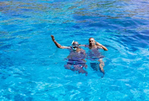 Two tourists snorkeling in crystal clear waters of Similan Islands.