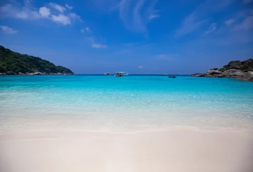Paradise beach of Similan Islands National Park with calm turquoise sea and anchored boats from Phuket tours.