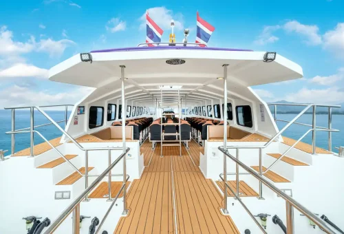 Spacious interior seating of Wow Andaman speed catamaran with Thai flags and ocean view.