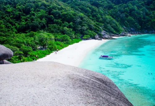 Secluded beach and speedboat anchored in turquoise water at Similan Islands, Thailand.