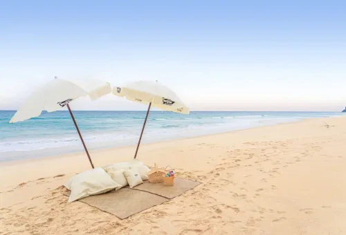 Private beach picnic setup with umbrellas and cushions at Khao Na Yak.