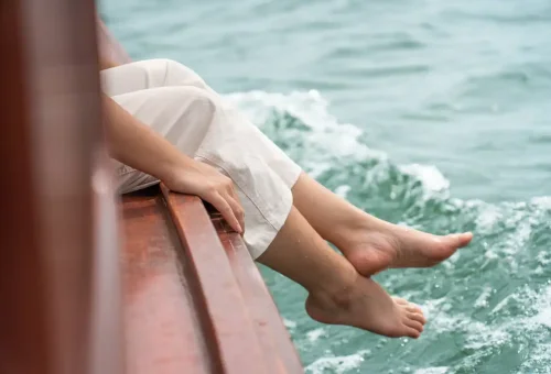 Feet over the side of a longtail boat enjoying the sea breeze.