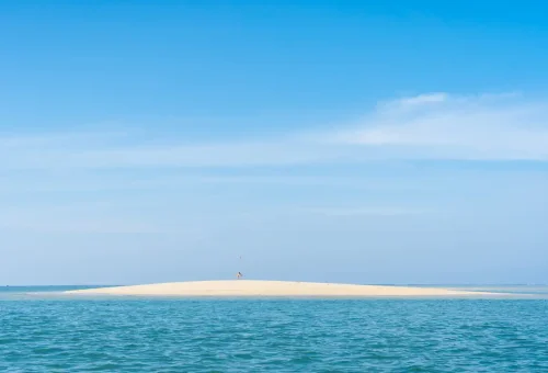 Small sandy island with turquoise waters, accessible only by private longtail boat from Phuket Travel Store.