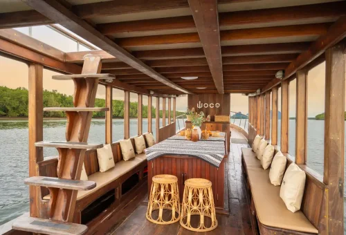Interior of WOW Woco private longtail boat set up with dining table and rattan stools in Phang Nga Bay.