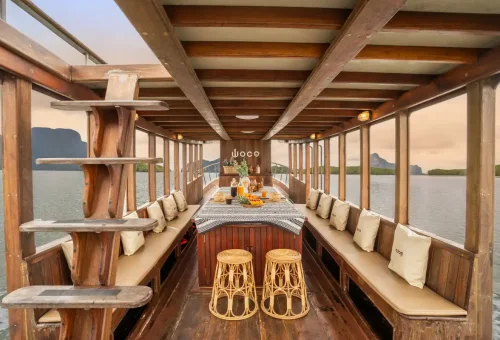 Elegant dining setup inside WOW Woco longtail boat with tropical fruits and drinks in Phang Nga Bay.