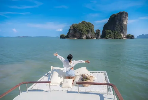 Woman relaxing on rooftop deck of WOCO boat with limestone island views.