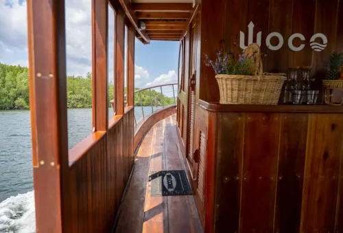 Wooden side deck of WOCO private boat with basket of flowers.