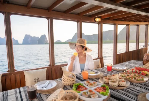 Woman enjoying Thai snacks and tropical fruits on WOCO boat in Phang Nga Bay.