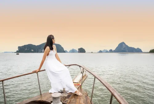 Woman in white dress enjoying the deck of a private boat in Phang Nga Bay.