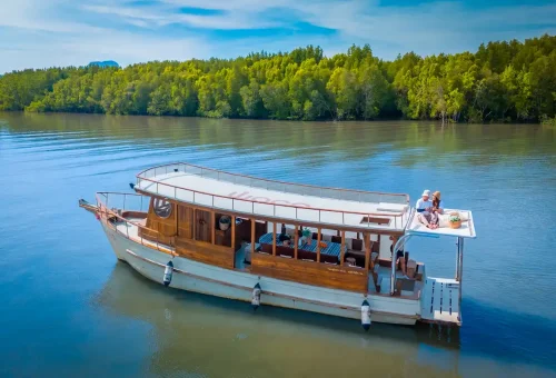 Couple relaxing on roof deck of private longtail boat
