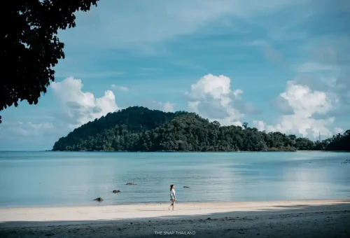 Woman walking on pristine Surin Islands beach with turquoise waters.