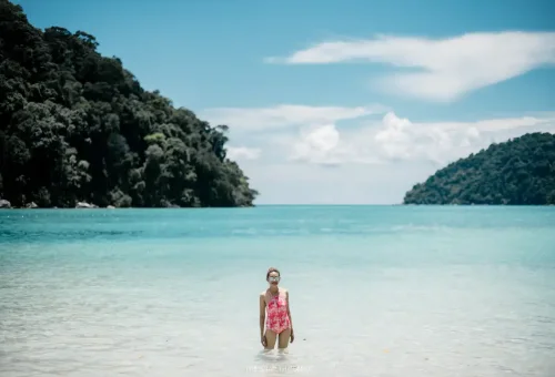 Tourist standing in crystal-clear Surin Islands lagoon.