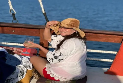 Guest with sun hat smiling and enjoying a drink onboard