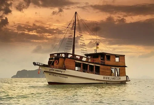 Traditional Phuket wooden boat cruising at sunset