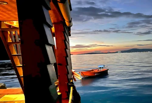 Wooden boat at twilight floating in calm Phuket waters
