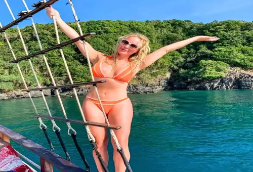 Guest posing on traditional wooden boat in clear blue waters